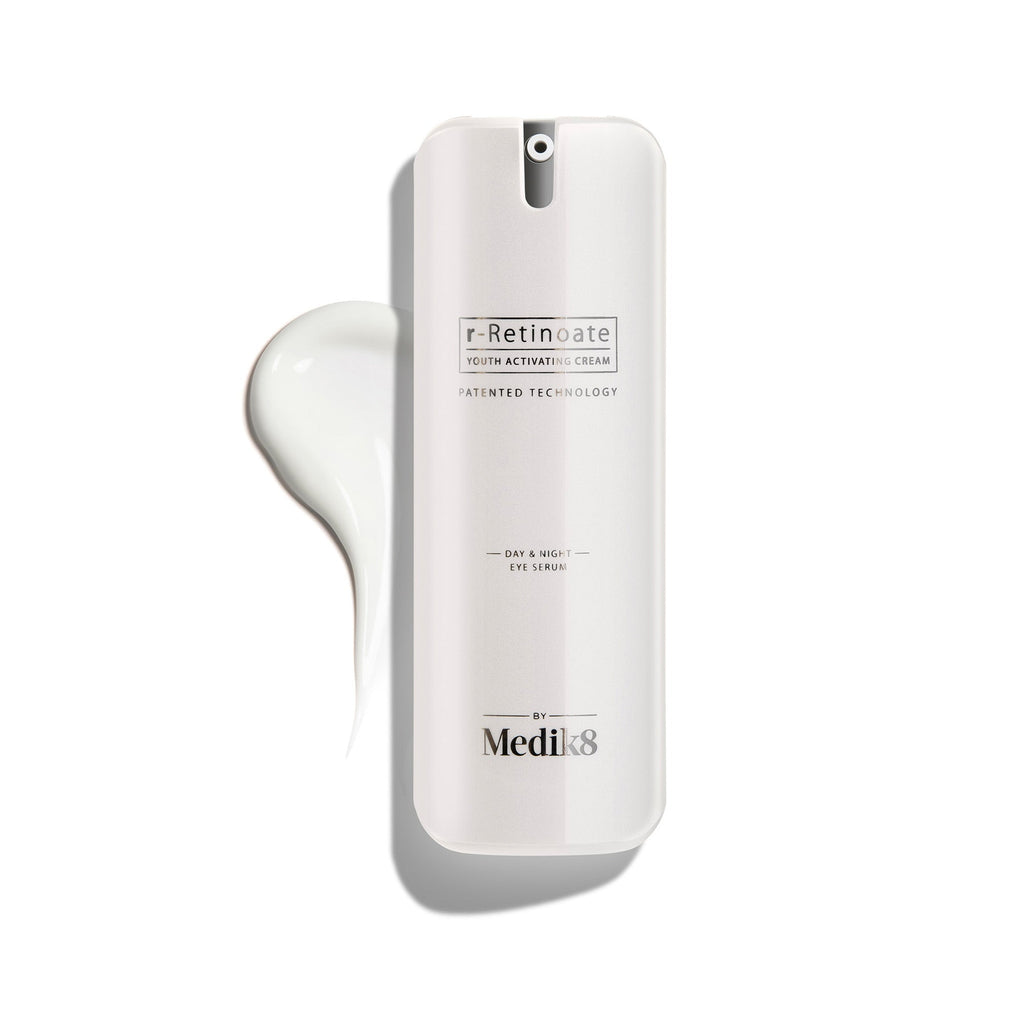 Een witte pompflacon van r-Retinoate Day & Night Eye Serum, met daarnaast een druppel van het product.