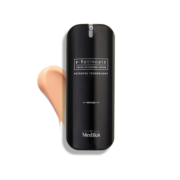 Een flacon Medik8 r-Retinoate Intense Youth Activating Cream gepresenteerd op een witte achtergrond, met daarachter een zichtbare veeg van de perzikkleurige crèmetextuur.-2