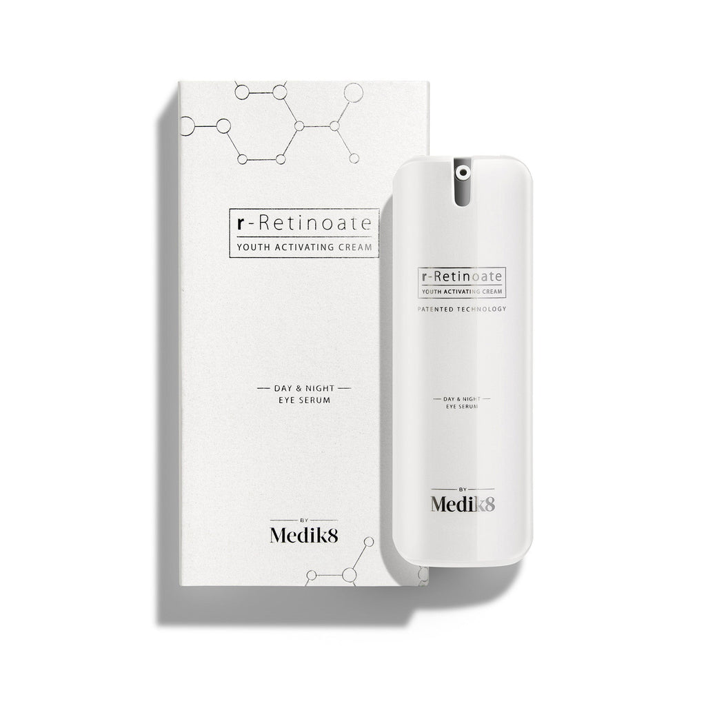 Een witte pompflacon van r-Retinoate Day & Night Eye Serum staat naast de bijbehorende witte kartonnen verpakking.
