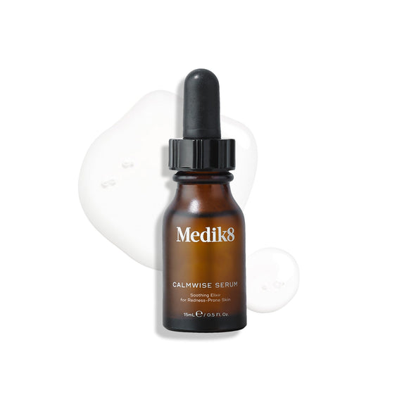 Een bruine glazen pipetfles van Calmwise Serum staat rechtop op een wit oppervlak, omringd door heldere druppels van het serum.-6