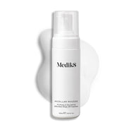 Een pompflacon Medik8 Micellar Mousse tegen een witte achtergrond met daarachter een veeg van wit schuim die de textuur van het product laat zien.