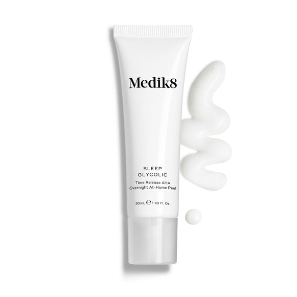 Een tube Medik8 Sleep Glycolic tegen een strakke witte achtergrond, geflankeerd door een golvende veeg en een druppel witte crème-textuur. De tekst vermeldt dat dit een 'Time Release AHA Overnight At-Home Peel' is in een formaat van 30 ml.-2