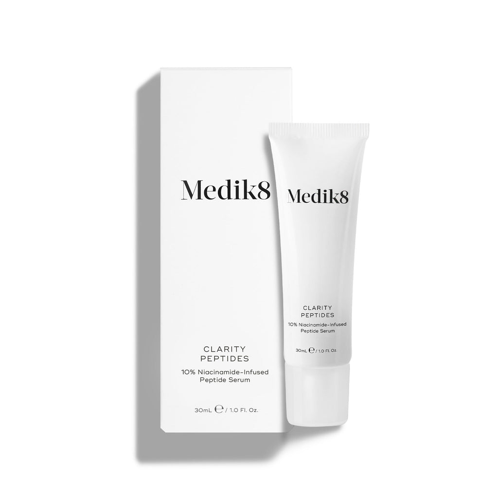 Een tube Medik8 Clarity Peptides staat naast de witte kartonnen omverpakking op een witte achtergrond. De tekst identificeert het product als een 10% Niacinamide-Infused Peptide Serum in een formaat van 30 ml.