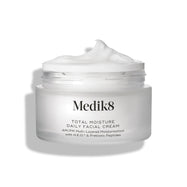 Een open, matglazen pot van Medik8 Total Moisture Daily Facial Cream met een toef witte crème bovenop, geplaatst tegen een strakke witte achtergrond.