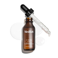 Een geopend flesje Medik8 C-Tetra Luxe serum met de glazen pipet rustend tegen de rand, getoond tegen een witte achtergrond met heldere, transparante serumdruppels.