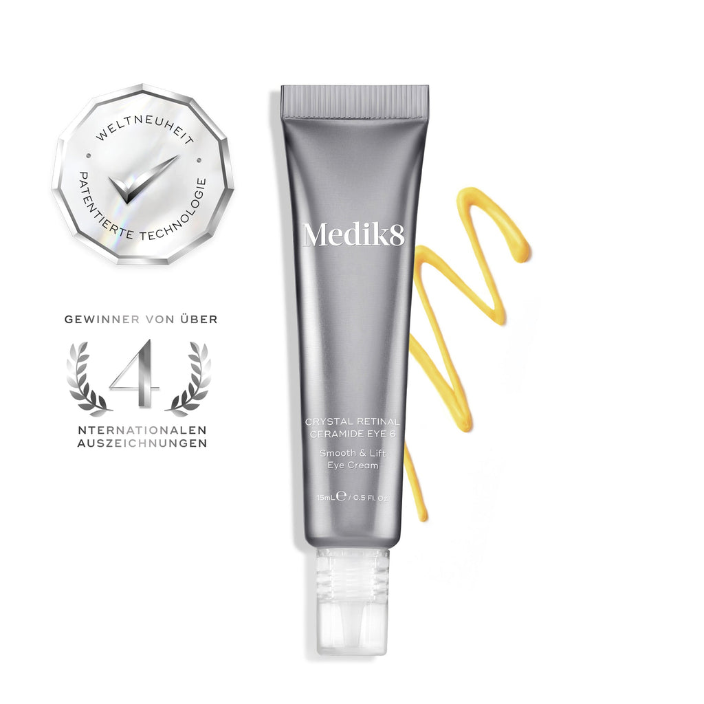 Een zilveren tube Crystal Retinal Ceramide Eye 6 staat rechtop, met daarnaast een swirl van geel-oranje crème aan de rechterkant.
