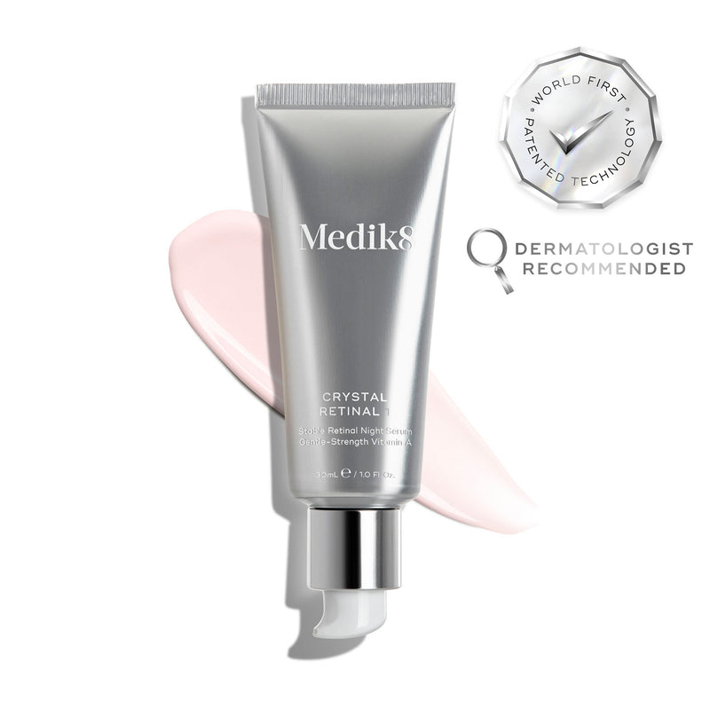 Een zilverkleurige tube Medik8 Crystal Retinal 1 wordt getoond, met rechts daarvan een roze crèmeswatch. Er worden een zegel met “WORLD FIRST PATENTED TECHNOLOGY” en een icoon “DERMATOLOGIST RECOMMENDED” weergegeven.