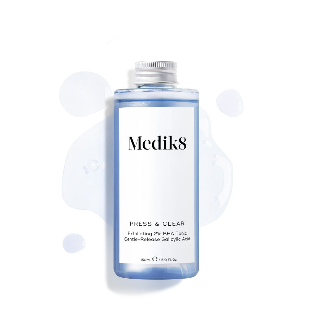 Een navulfles (150 ml) van de Medik8 Press & Clear tonic met een zilveren schroefdop, weergegeven op een witte achtergrond met blauwe vloeistofdruppels. Tekst bevestigt dat het Gentle-Release Salicylic Acid bevat.